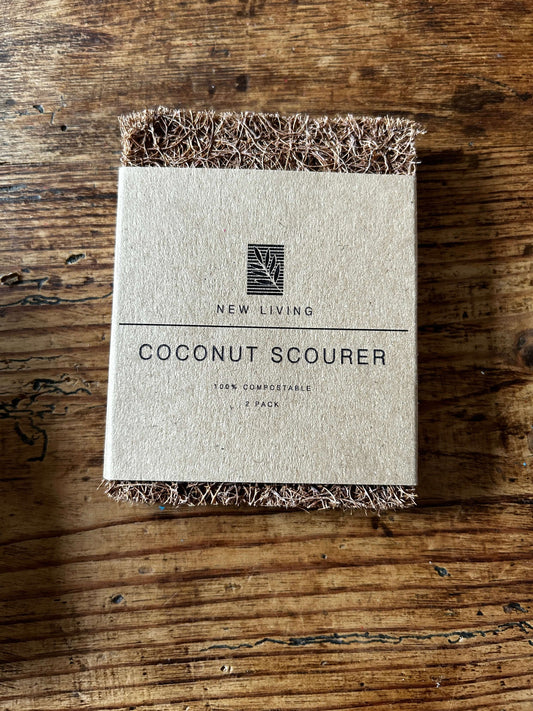 Eco-friendly coconut scourer on wooden table, promoting sustainable cleaning tips in the UK.