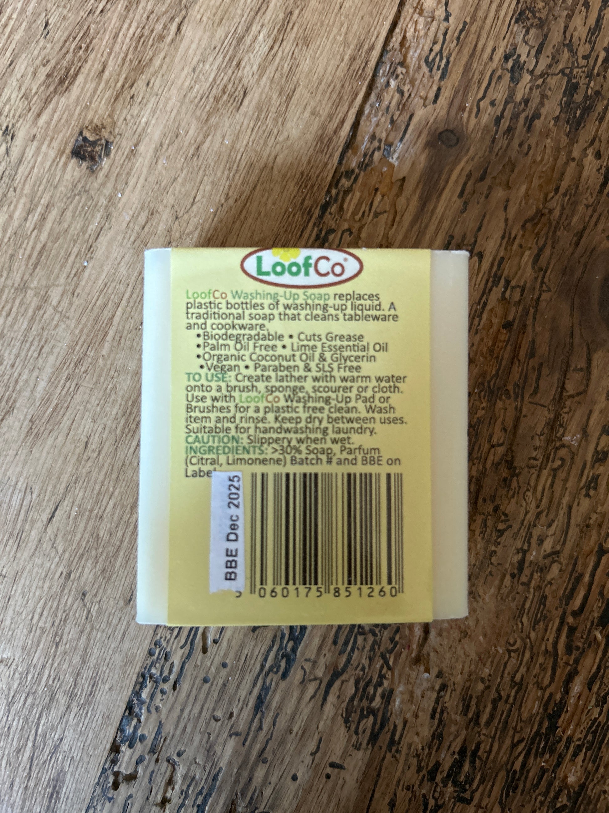 Back view of LoofCo Washing Up Solid Bar Soap - Lime on a wooden surface, showing label and barcode.