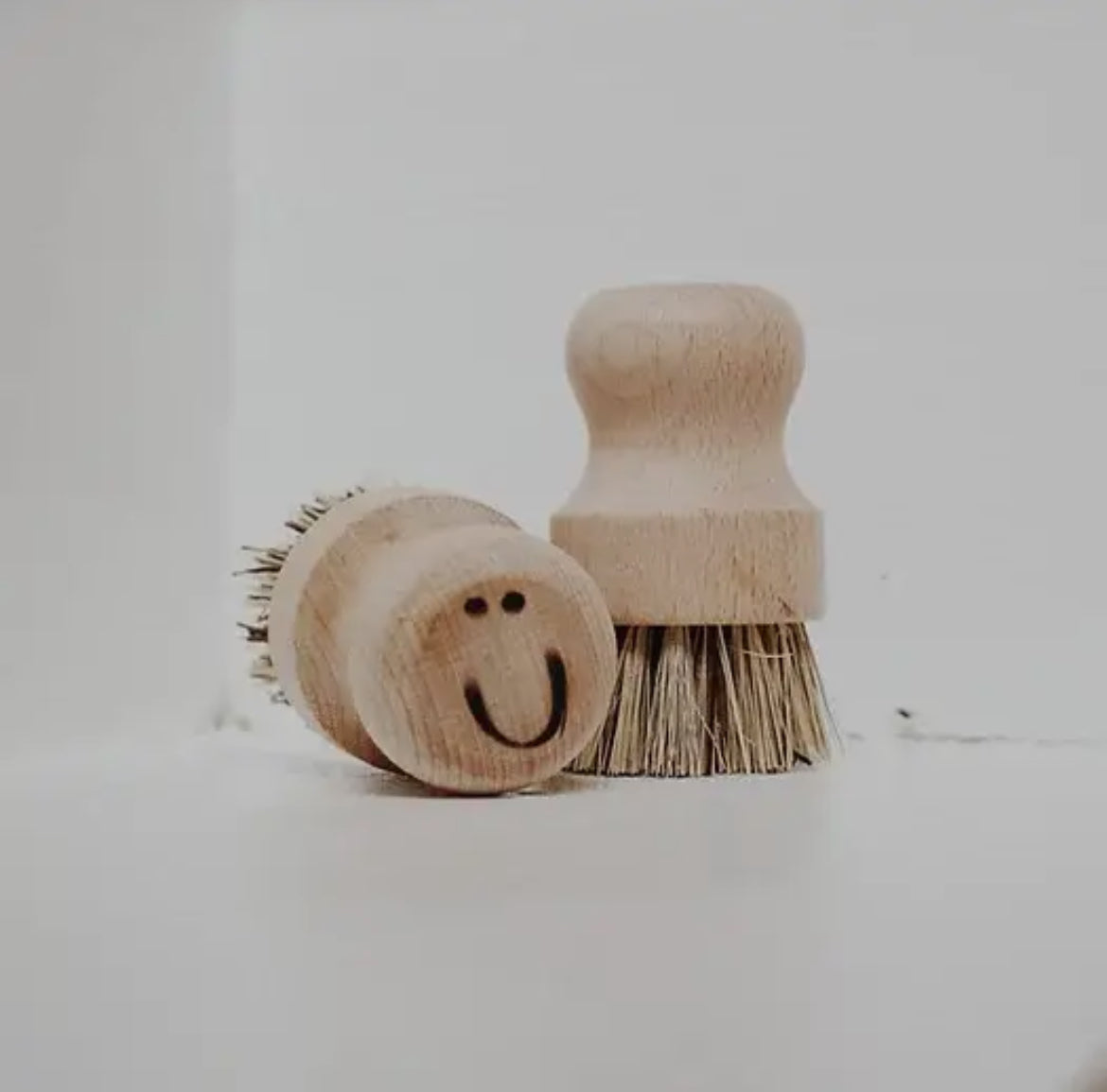 Handmade pot brush with happy face etching, crafted with care for joyful dishwashing.