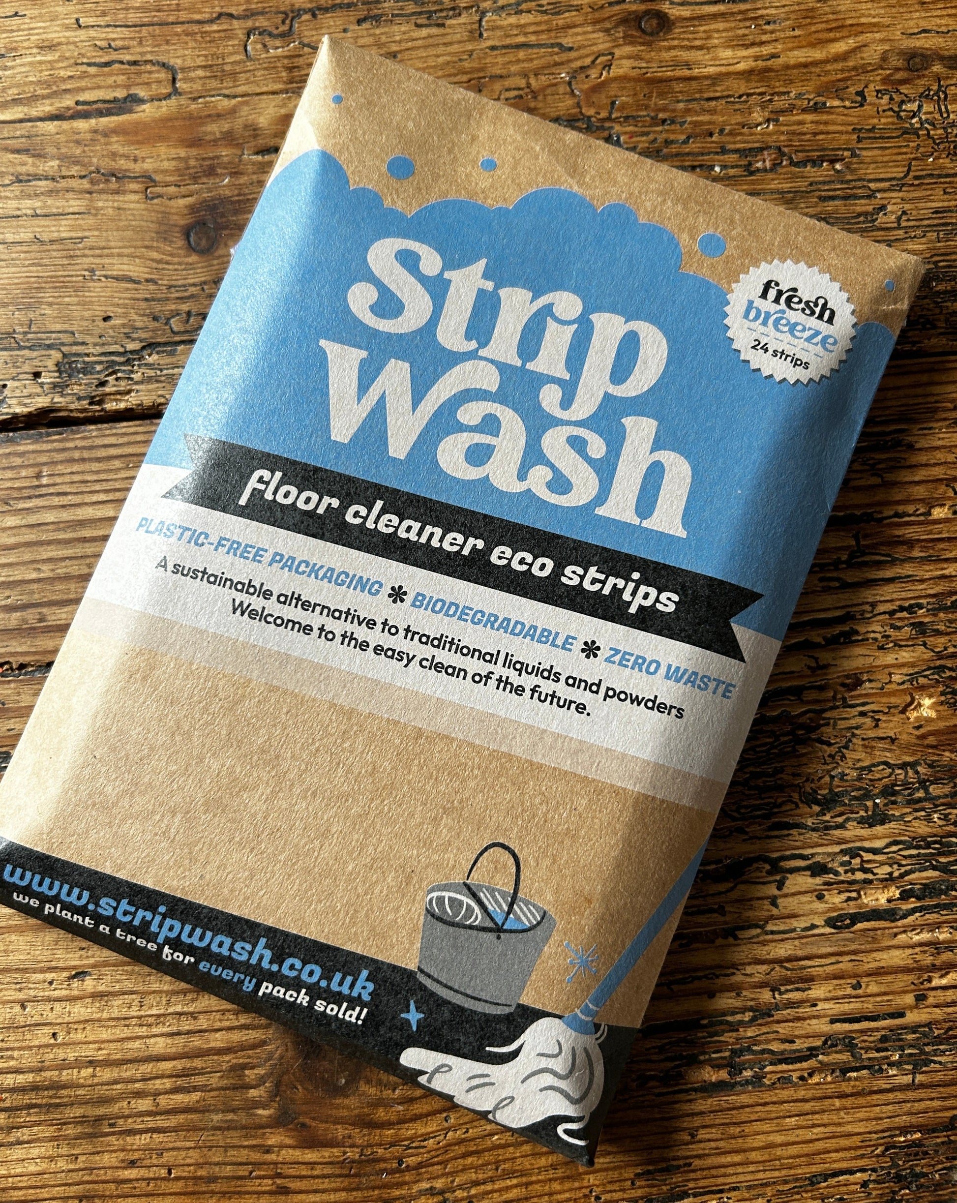 Strip Wash floor cleaner eco strips in plastic-free packaging on wooden surface. Biodegradable, zero-waste, and sustainable.