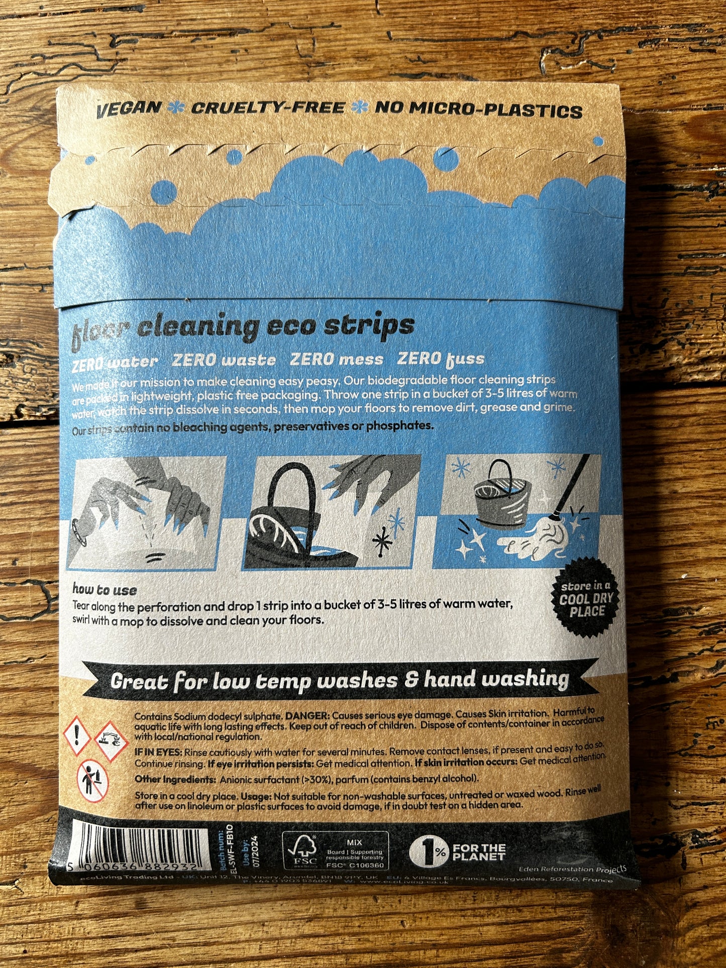 Packaging of Strip Wash Floor Cleaning Eco Strips displaying vegan, cruelty-free, and no micro-plastics features on a wooden surface